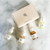 Skincare serum discovery kit with bottles and a box on a marble surface