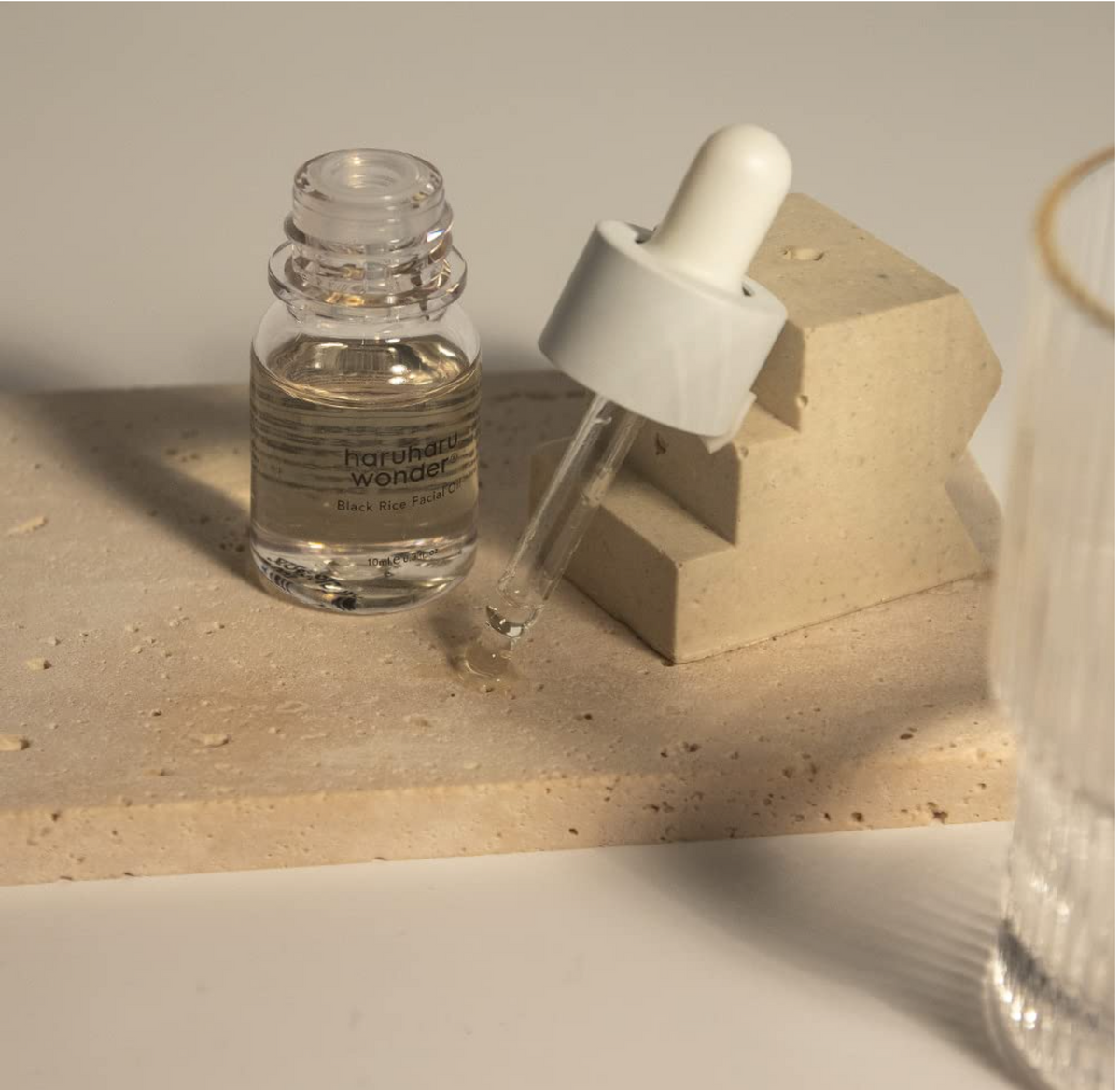 Haruharu Wonder Black Rice Facial Oil Mini 10ml dropper bottle on beige stone background