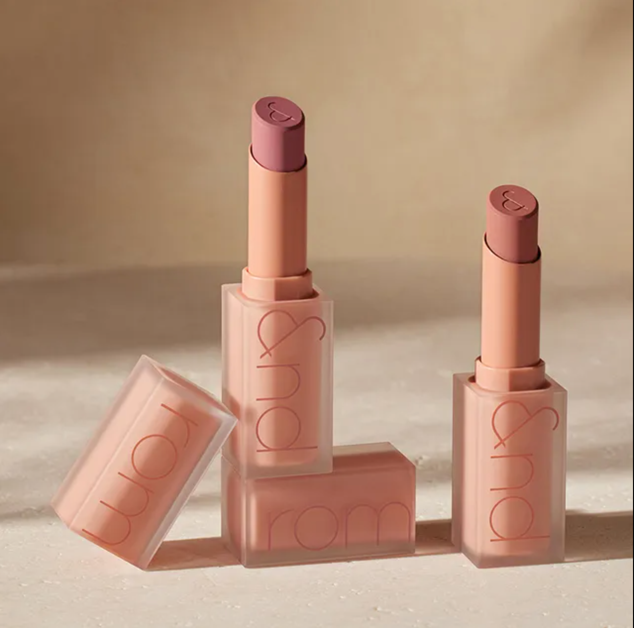 Lipstick with open case on a beige background